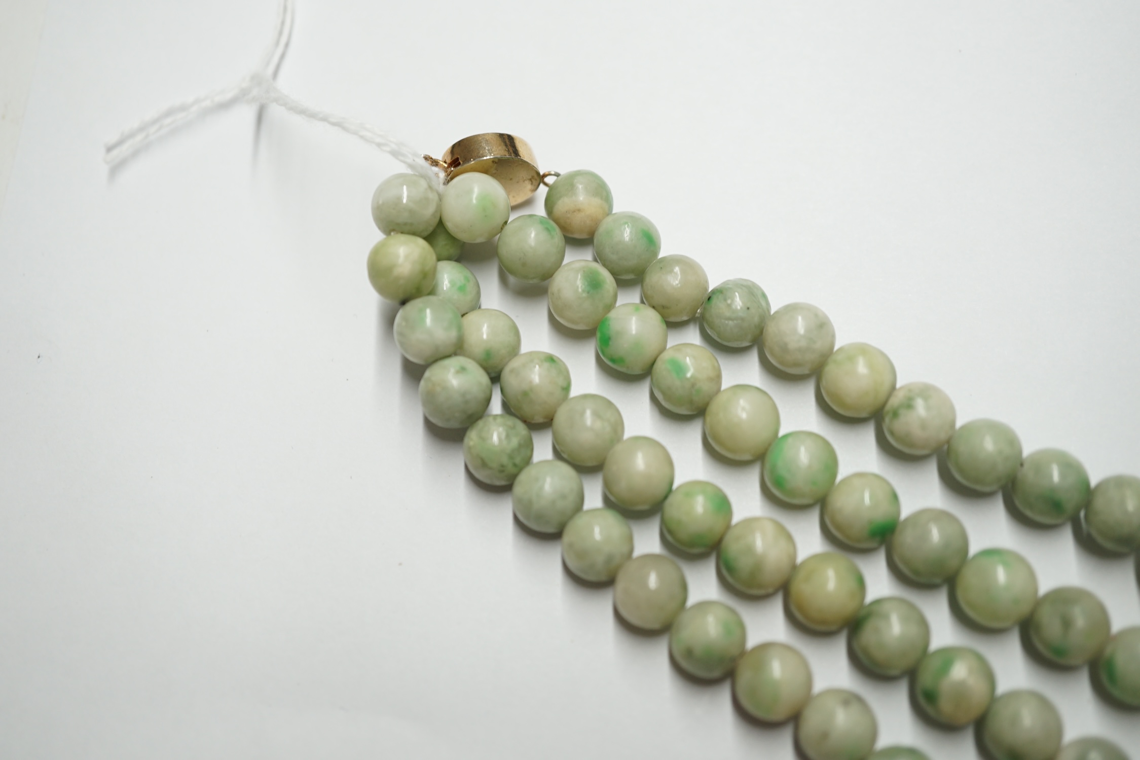 A double strand jade bead choker necklace, with cabochon jade set yellow metal clasp, 38cm. Condition - poor to fair